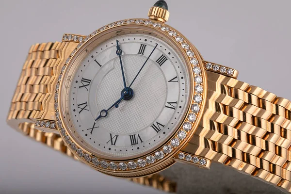 Reloj de mujer, con correa de metal de oro, diamantes con esfera blanca, números negros y agujas azules aislados sobre fondo blanco . — Foto de Stock