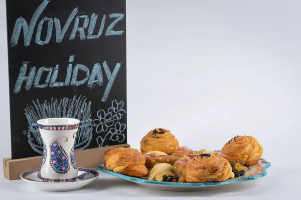 Şenlikli tatil Navruz.Shekerbura, baklava, bir plaka üzerinde tuzlu dolgulu puf böreği için pişirme. Beyaz cam armudu buta mavi bir baskı ile.