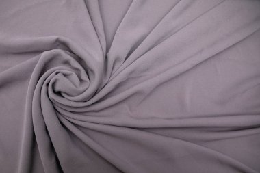 Masanın üzerine yayılmış ve hafifçe bükülmüş gri kumaş.