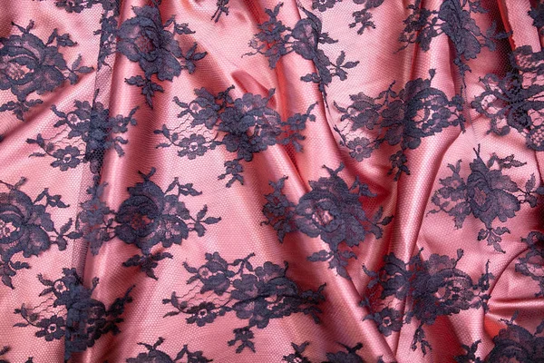 Tecido de tule com padrões pretos em cima de tecido rosa espalhados na mesa — Fotografia de Stock