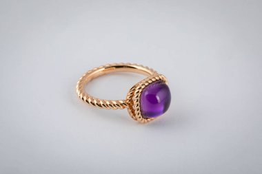 Female, yellow gold ring with purple stone in the middle, isolated on a white background. clipart