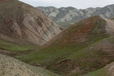 Tepeler ve dağlar gökyüzüne karşı yamaçlarda kırmızı çizgiler ile bitki örtüsü ile kaplı.