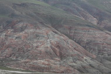 Gökyüzüne karşı yamaçlarda kırmızı çizgili bitki örtüsü ile kaplı dağlar.
