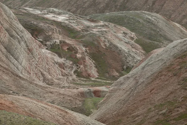 Tepeler ve dağlar gökyüzüne karşı yamaçlarda kırmızı çizgiler ile bitki örtüsü ile kaplı.