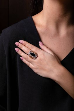 Kadınların altın yüzüğü. Ortasında siyah bir taş var. Siyah bir arka planda..