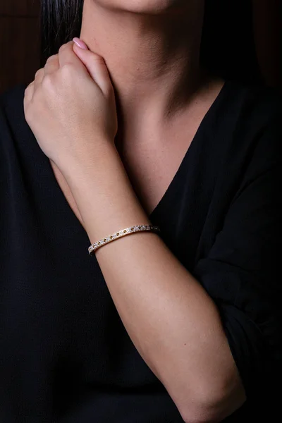 Gold female bracelet on hand with stones on a black background. — Stock Photo, Image