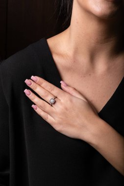 Kadınların gümüş halkası. Ortasında taşlar var. Parmağında kare şeklinde, siyah bir arka planda..