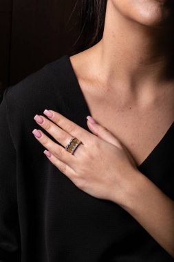 Parmak kenarlarında taşlar ile Kadın altın yüzük, siyah bir arka plan üzerinde.