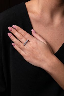 Kadınların gümüşü, parmağında elmas yüzük, siyah arka planda.