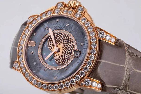 Montre bracelet doré avec cadran gris avec motifs, dans le sens des aiguilles d'une montre dorée, chronographe sur bracelet en cuir brun sur fond blanc — Photo
