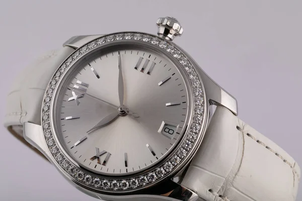 Montre femme argentée avec un cadran gris clair, argent dans le sens des aiguilles d'une montre, chronographe, avec un bracelet en cuir blanc isolé sur fond blanc Photo De Stock