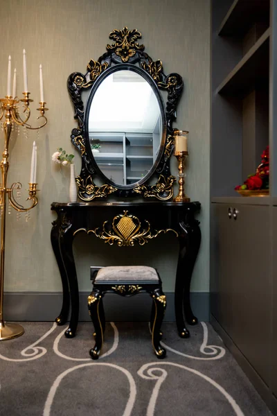 Un espejo en un marco negro sobre una mesa con patas, de pie en una esquina de la habitación . —  Fotos de Stock