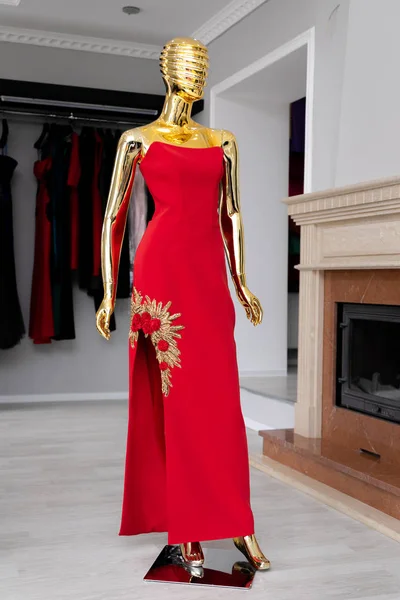 Vestito femminile, rosso lungo con ornamento da perline d'oro su un manichino d'oro . — Foto Stock