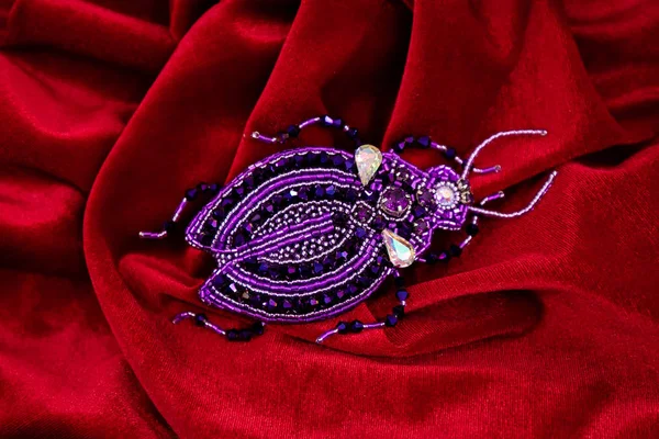 Καρφίτσα σχεδιαστή κατασκευασμένο από χειροποίητα κοσμήματα σε σχήμα ενός bug απομονώνεται σε κόκκινο φόντο. — Φωτογραφία Αρχείου