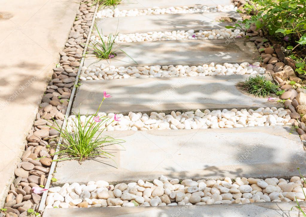 Landscape modern simple stone pathway in garden decoration with white,brown pebbles  and pink rain lily flowers