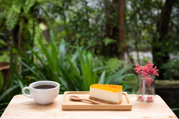 Passion fruit cheesecake and hot coffee cup on wooden tray and t