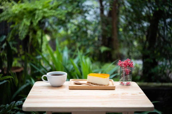 Passion fruit cheesecake and hot coffee cup on wooden tray and t
