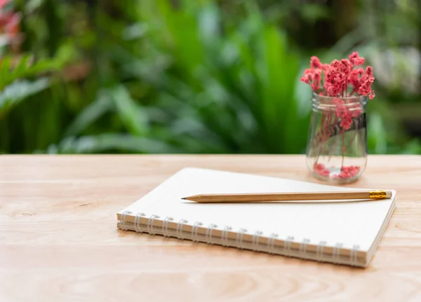 Poznámkový blok, hnědý tužka a krásná rudá sušená květina ve skleněné vě — Stock fotografie
