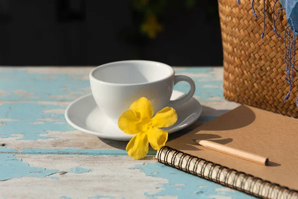 Šálek kávy na dřevěnému stolku s hnědým poznámkovým blokem, s rachlem a — Stock fotografie