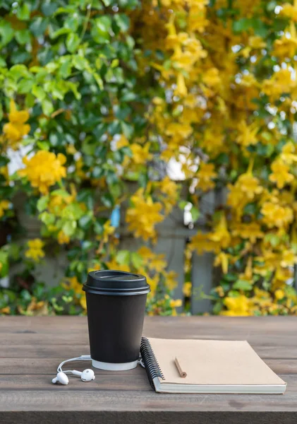 Tazza da caffè nera, auricolare bianco, taccuino per appunti e matita su legno — Foto Stock