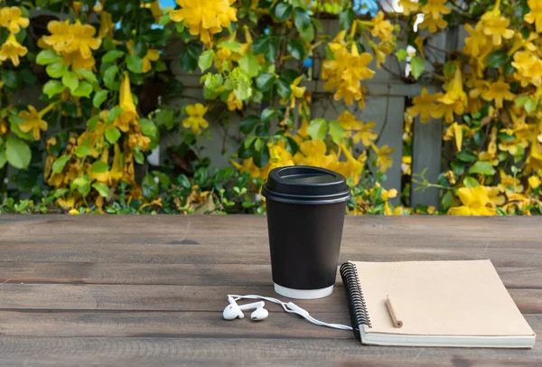 Taza de café negro, auriculares blancos, cuaderno de notas y lápiz en madera — Foto de Stock