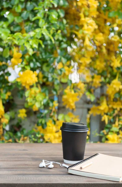 Black coffee cup,white earphone,memo notebook and pencil on wood — Stock Photo, Image