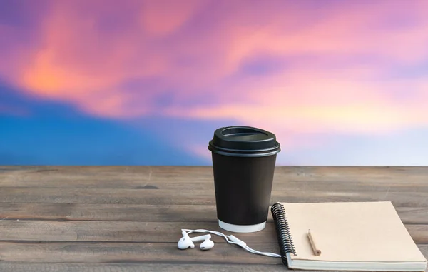 Coffee cup,ear phone and notebook on wooden top withbeautiful pi — Stock Photo, Image