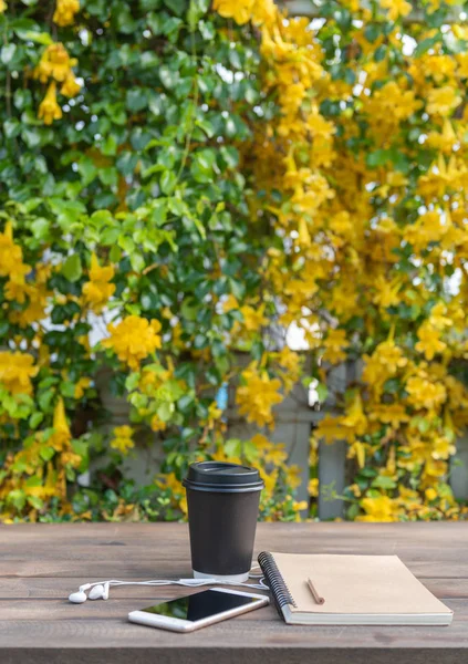 Tazza da caffè nera, auricolare bianco, taccuino per appunti e matita su legno — Foto Stock