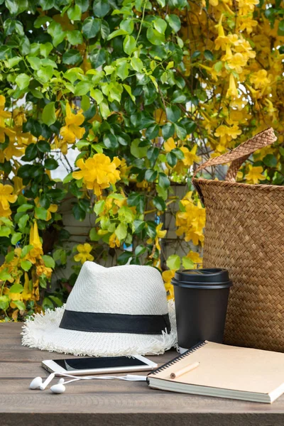 Koffie kopje, notebook, telefoon, Panama hoed en rotan tas op houten ta — Stockfoto