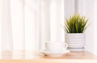 Morni ile ahşap ofis masası üzerinde beyaz kahve fincanı ve bitki demliği