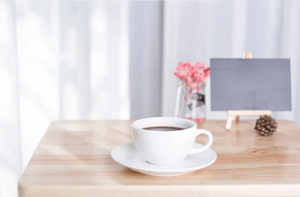 Kaffekopp och svart kartong på kontorsbord med vit gardin b — Stockfoto