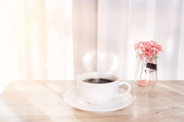 Tasse à café blanche avec fumée, fleur rouge séchée sur bureau en bois d — Photo