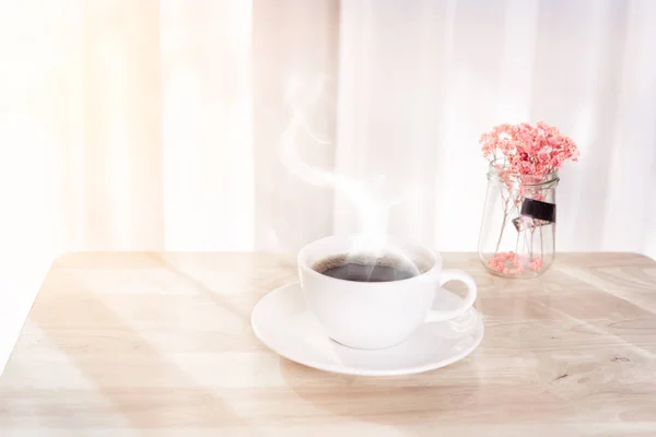 Tasse à café blanche avec fumée, fleur rouge séchée sur bureau en bois d — Photo