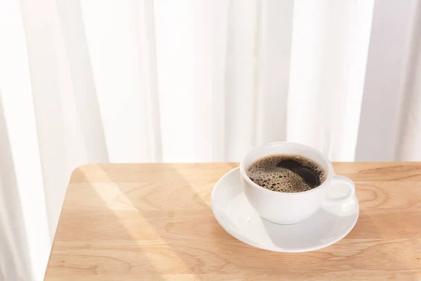 Weiße Kaffeetasse auf hölzernem Schreibtisch mit Morgensonne — Stockfoto