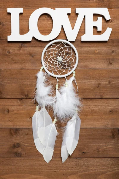 White dream catcher and love text on wooden background, flat lay — стоковое фото