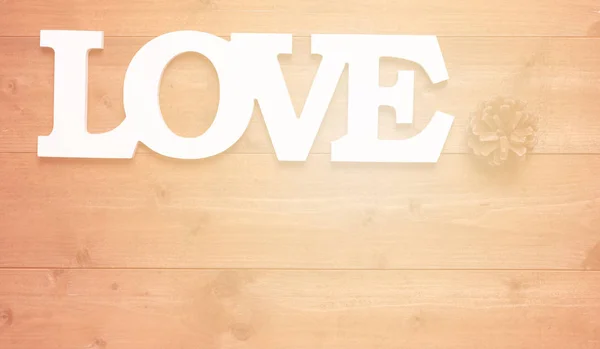 木製の背景に白い愛のテキストと松のコーンの装飾 — ストック写真