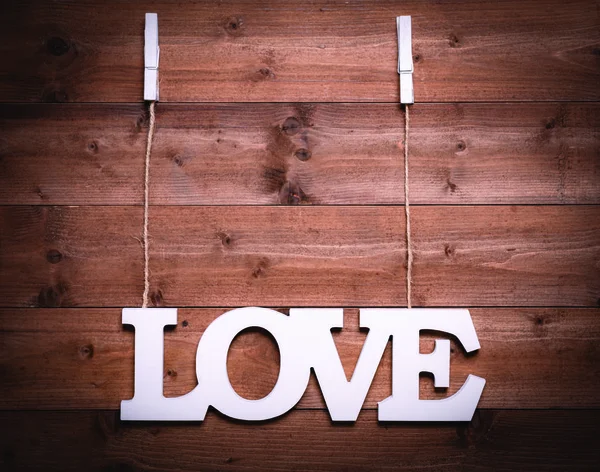 Vit kärleks text hänga med rep och klädnypa på trä bakgrun — Stockfoto