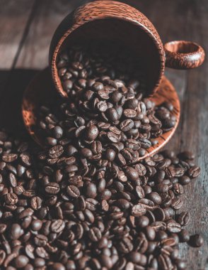 Ahşap arka planda ahşap fincan kavrulmuş kahve çekirdekleri