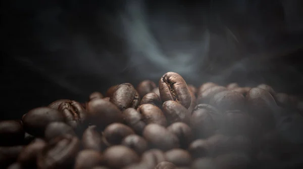 Aroma chicchi di caffè torrefatto con fumo che sale su backgroun scuro — Foto Stock