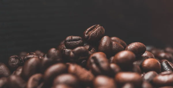 Жареный кофе в зернах с темным фоном — стоковое фото