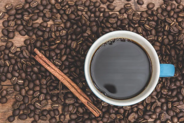 Xícara de café azul, canela, anis estrela e grãos de café em madeira b — Fotografia de Stock