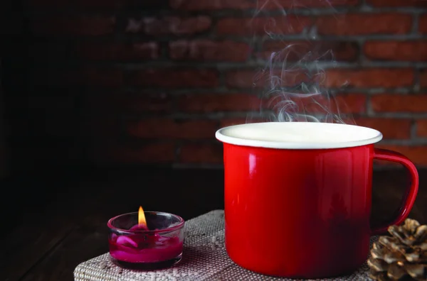 Xícara de café vermelho, rosa vela, notebook e pinho cone na mesa de madeira — Fotografia de Stock