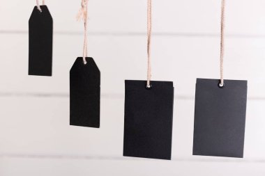 Kahverengi ipli boş siyah etiket beyaz ahşabın arkasında asılı.