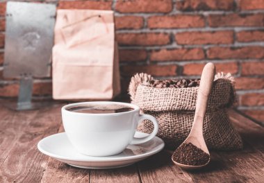 Kahve fincanı, kahve fincanı ve ahşap masada çuval bezeli kahve çekirdekleri!