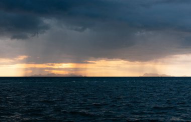 Büyük yağmur bulutları ve altın ışık gökyüzü ile güzel plaj gün batımı