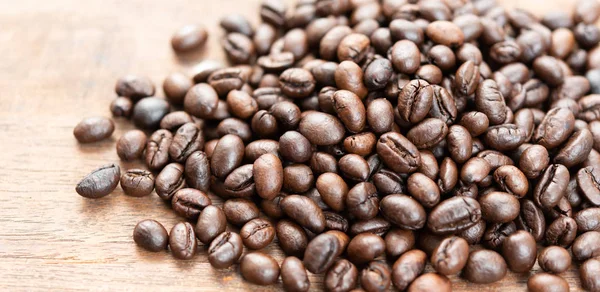 Geröstete Kaffeebohnen auf Grunge-Holz-Tisch Hintergrund — Stockfoto