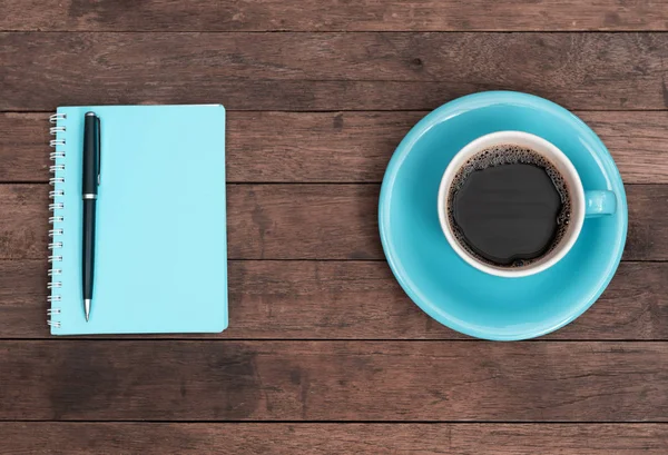 Blue coffee cup,pen and notebook on grunge wooden table top back — Stock Photo, Image