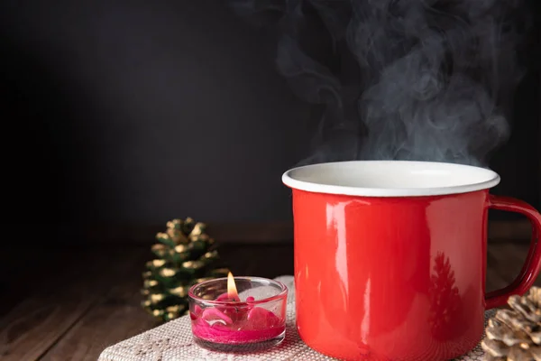 Xícara de café vermelho, rosa vela, notebook e pinho cone na mesa de madeira — Fotografia de Stock