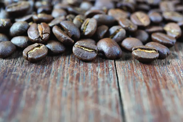 Смажені кавові зерна на гранжевому дерев'яному столі фоні — стокове фото