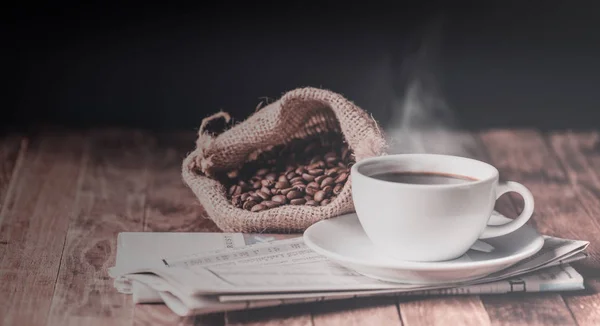 Kaffekopp med rökstegring, rostade kaffebönor och tidning — Stockfoto